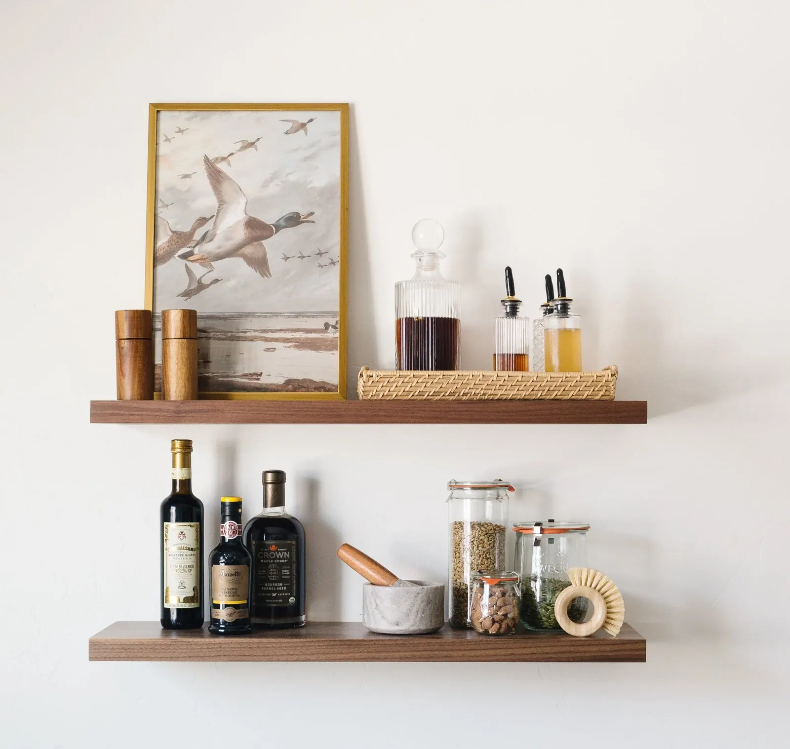 A warm-toned floating shelf styled as a small bar with bottles, jars, and framed art. Photo from ultrashelf.com.